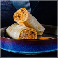 200 gram malse kippendijen met de hand geplukt. gemarineerd in onze huisgemaakte chillisaus. Afgetopt met verse chedder van het kaaslokaal en warm uit de oven geserveerd. <br><br><i>BiggBoss pulled chili chicken wrap</i>!