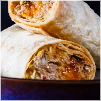 200 gram malse kippendijen met de hand geplukt. gemarineerd in onze huisgemaakte chillisaus. Afgetopt met verse chedder van het kaaslokaal en warm uit de oven geserveerd. <br><br><i>BiggBoss pulled chili chicken wrap</i>!