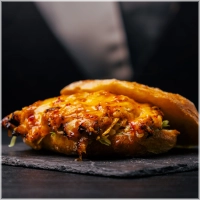 Malse pulled chili chicken rijk gemarineerd in onze huisgemaakte chillisaus, gesmolten cheddar, verse ijsbergsla en afgewerkt met onze eigen chillisaus<br><i> voor een extra kick kun je extra sambal toevoegen.</i> 